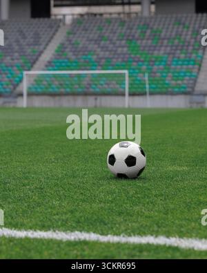 Soccer ball rests on the lush green pitch of a football stadium, awaiting the players to begin the game. Stock Photo
