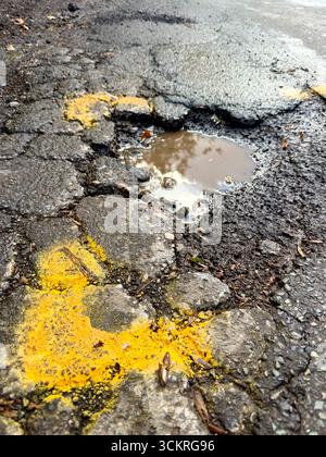 A pot hole identified and marked for repair on a road in the U.K. Stock Photo