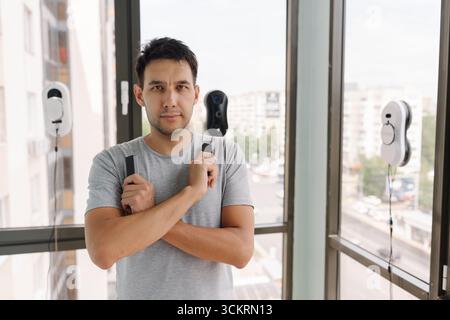 Portrait of confident window washer controlling robotic cleaning devices during high-rise exterior maintenance, showcasing advanced technological Stock Photo