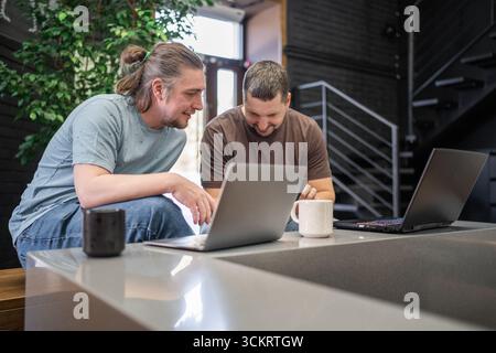 Two laughing It Software engineers working on project and programming in coffee shop. Successful start up project concept. Stock Photo