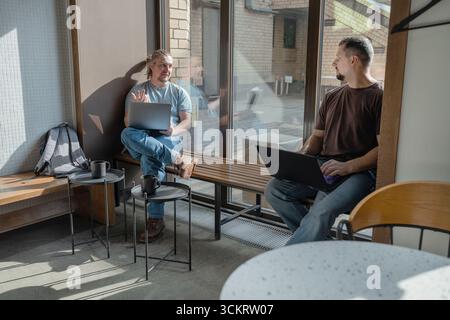 Programmers discussing over laptop working at startup. Office, business and friends together in teamwork with notebook, laptop and coffee workplace Stock Photo