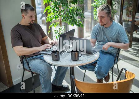Two It Software engineers working on project and programming in coffee shop. Business people concept. Stock Photo