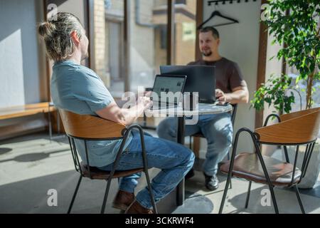 Two laughing It Software engineers working on project and programming in coffee shop. Successful start up project concept. Stock Photo