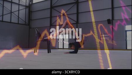 Stretching contortionist bending on chair and forearms in industrial hall with neon graph overlays Stock Photo