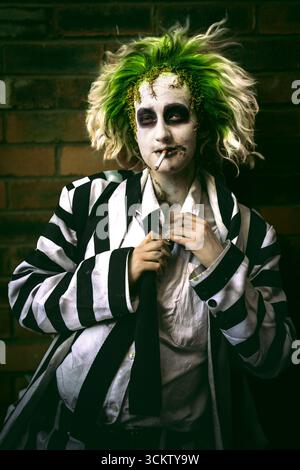 Close up portrait of a young male cosplayer laughing and having fun dressed as Beetlejuice with face paint and green hair Stock Photo