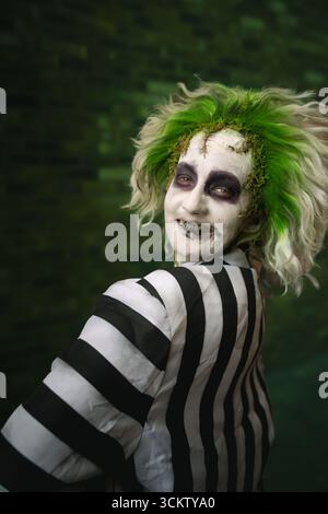 Close up portrait of a young male cosplayer laughing and having fun dressed as Beetlejuice with face paint and green hair Stock Photo