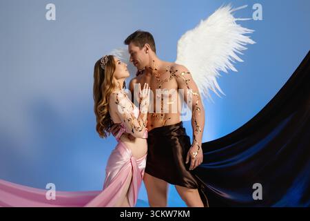 Couple in dramatic costumes pose together against a blue background Stock Photo