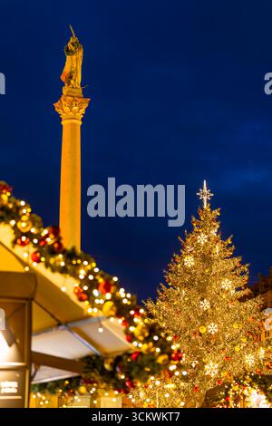 Christmas tree with golden decorations and Marian column at dusk during Christmas market in Prague Old Town Square, Czech Republic Stock Photo