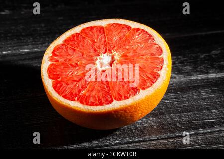 sliced grapefruit on black wood background Stock Photo