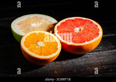 sliced citrus fruit mix on black wood background Stock Photo