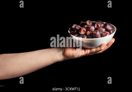 dates fruit in hand on black background Stock Photo