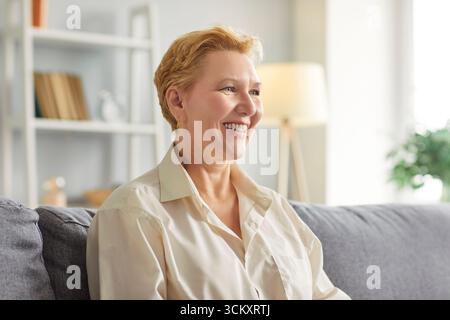Happy smiling senior woman sitting on sofa, laughing, having fun and enjoying conversation at home. Stock Photo