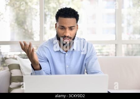Busy young man working remotely talking by videocall using notebook Stock Photo