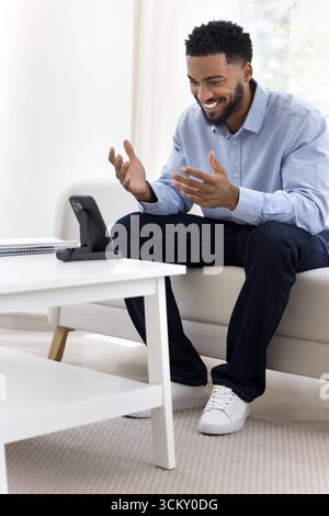 Smiling young guy speak by videocall using phone on holder Stock Photo