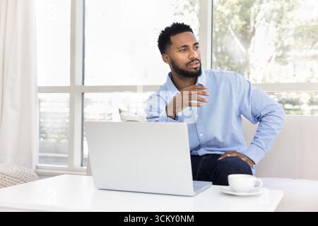 Serious pensive young man working on notebook from home office Stock Photo