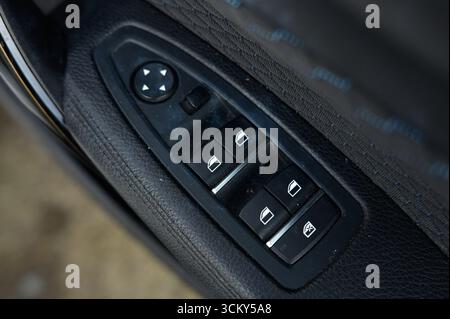 electric window control switches inside a modern car, focusing on the drivers side door panel Stock Photo