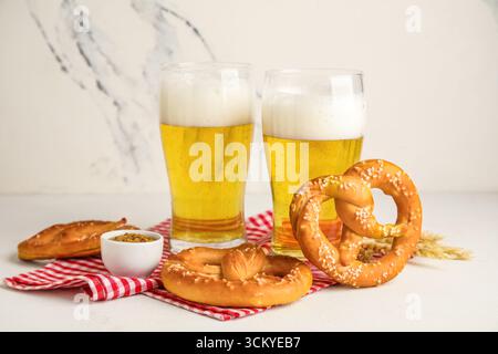Pretzels and glasses of cold beer on marble background, closeup Stock Photo