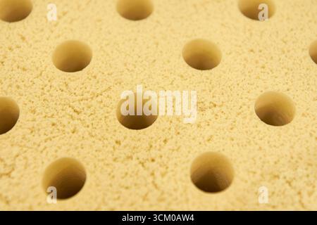 Textured yellow sponge close-up with uniform circular holes for cleaning or crafting. Stock Photo