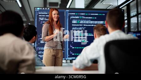 Executive Coder Gives Presentation To Diverse Team In Boardroom Stock Photo