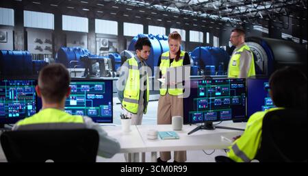 Diverse Group Of Young Engineers Learning SCADA Operations At Power Plant. Stock Photo