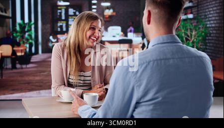 Young Writer Sipping Tea And Collaborating With Therapist At Cafe. Stock Photo