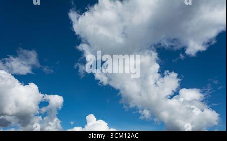 White clouds scattered around a vivid blue sky forming a circular opening that creates a dynamic and atmospheric scene Stock Photo