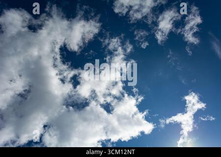 White clouds scattered around a vivid blue sky forming a circular opening that creates a dynamic and atmospheric scene Stock Photo