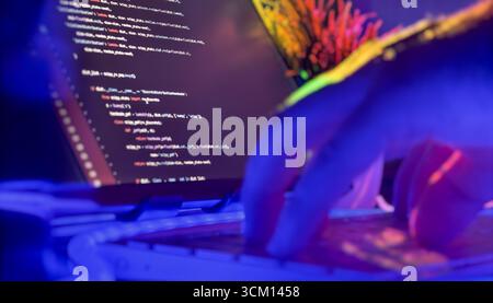 Close-up of hands typing Python code on keyboard in a vibrant, neon-lit environment, representing modern software development and creativity. Stock Photo