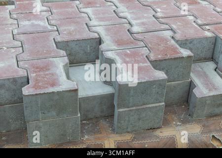 Interlocking concrete paving blocks in H shape stacked for sidewalk and driveway construction material background industry supply. Stock Photo