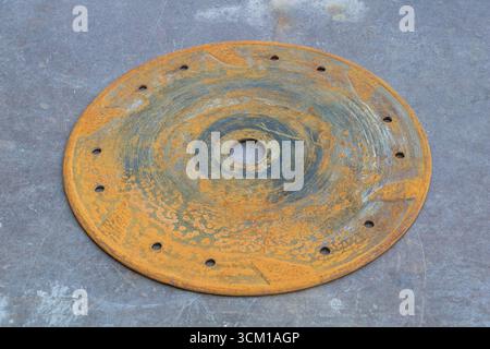 Rusty circular metal disc with holes corrosion texture industrial background old machinery spare part. Stock Photo
