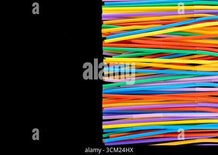 Vertical Cluster of Colorful Plastic Straws on Right Side Against Black Background. Stock Photo