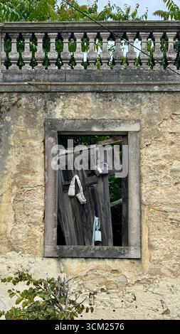 Broken wooden window set in a limestone wall with balustrading along the top Stock Photo