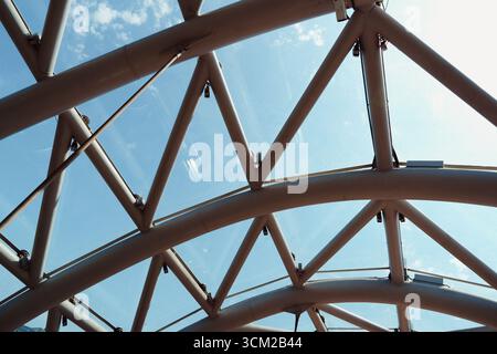 Architectural design featuring a glass and steel structure against blue sky during daylight hours Stock Photo
