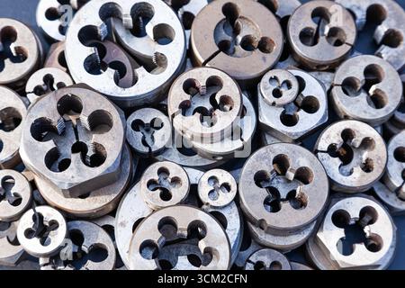Bolt threading dies. Many dies of different sizes, top view. Hand tool for making screw threads on bolts. Stock Photo