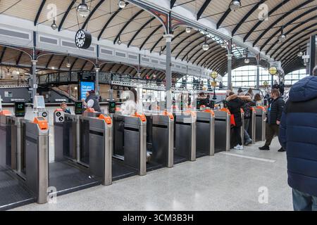 Commuters passing through ticket barriers in Newcastle Central Stationwith a high arched ceiling and digital display screens Stock Photo