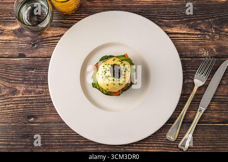 Gourmet eggs benedict with smoked salmon and caviar on white plate Stock Photo