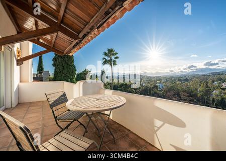 an image of a luxury balcony with wooden chairs and table and sunset landscape views over the mediterranean Stock Photo