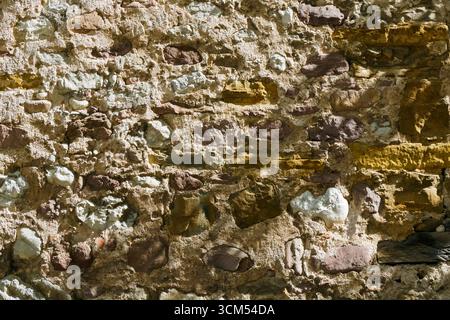 Close-up of an old stone wall built with irregular rocks and mortar, showing rough texture and rustic detail, perfect for backgrounds, design projects Stock Photo