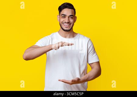 Positive muslim guy holding something invisible in his hands Stock Photo