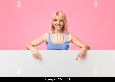 Look there. Happy woman pointing on blank white advertisement bo Stock Photo