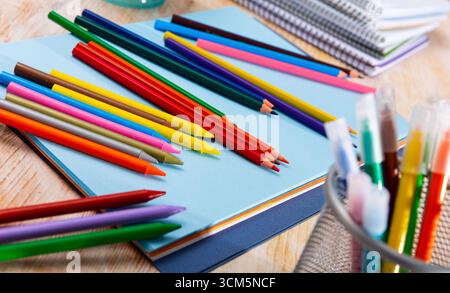 Multicolored pencils on table with papers and notebooks Stock Photo