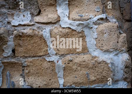 Close-up of a tuff block and concrete wall, typical of some buildings. Background and basic texture. Stock Photo