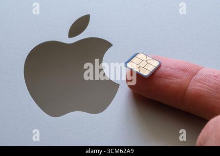 Apple logo and physical SIM card. Concept image for APPLE is killing physical SIM card releasing e-sim only iPhone 17 devices. Stock Photo