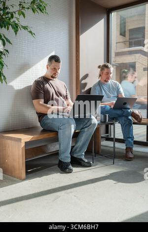 Programmers discussing over laptop working at startup. Office, business and friends together in teamwork with notebook, laptop and coffee workplace Stock Photo