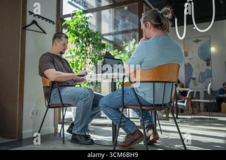 Two skilled professionals devops engaged in collaborative efforts within a contemporary workspace Stock Photo