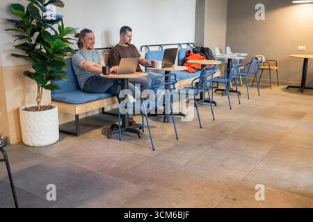 Two laughing It Software engineers working on project and programming in coffee shop. Successful start up project concept. Stock Photo