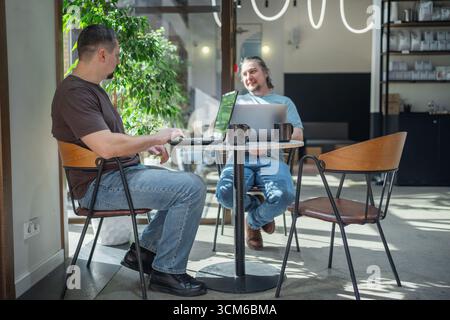 Programmers discussing over laptop working at startup. Office, business and friends together in teamwork with notebook, laptop and coffee workplace Stock Photo
