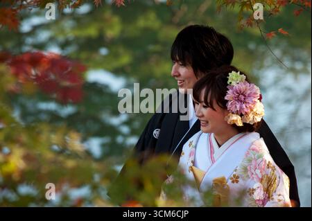 A Japanese newlywed bride and groom couple dressed in traditional wedding kimono pose at Genkyuen Garden in Hikone, Japan. Stock Photo