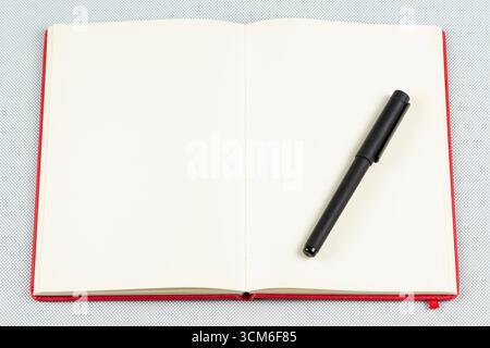 close up to a blanked notebook with a black pen over its right sheets Stock Photo