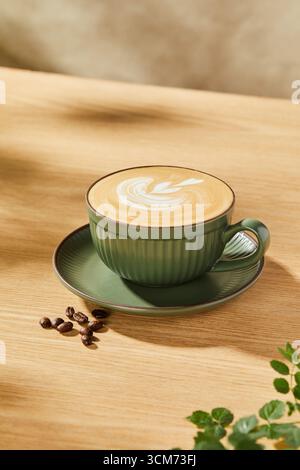Aromatic Latte in Green Ceramic Cup on Wooden Table, Cup of latte art coffee on wooden table, stock photo Stock Photo